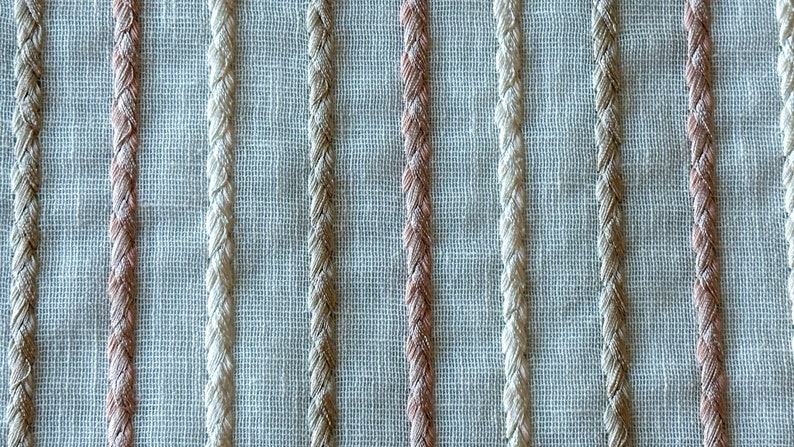 Puede incluir: Primer plano de una tela tejida con rayas alternas de color beige y rosa claro.