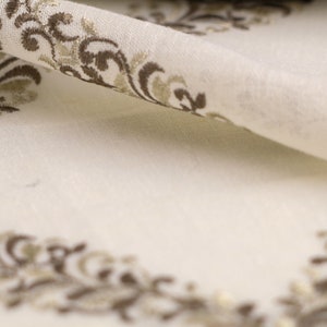 May include: White fabric with a brown and gold embroidered floral pattern.