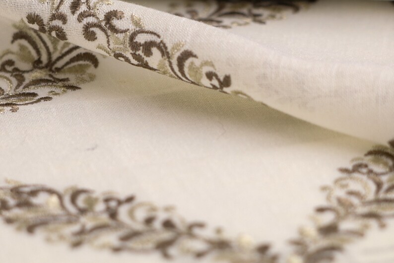 May include: White fabric with a brown and gold embroidered floral pattern.