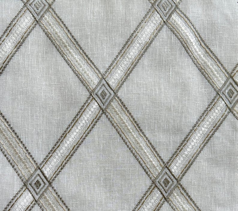 May include: A white fabric with a diamond pattern woven in a light brown thread.