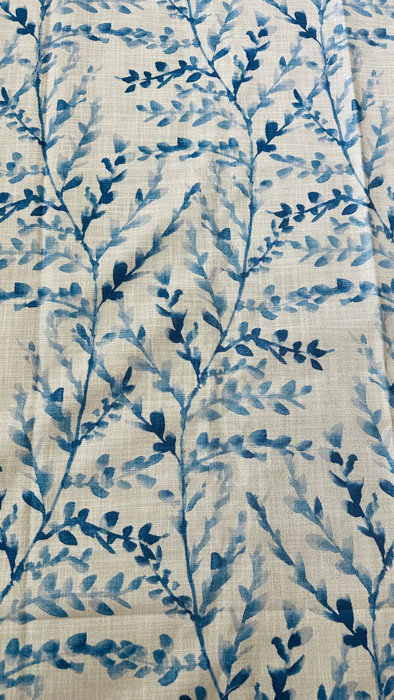 May include: Close-up of fabric with a repeating pattern of blue watercolor-style branches and leaves against a neutral beige background. The design has a natural, botanical theme, suitable for home decor.