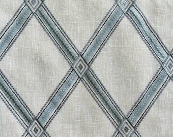 May include: A close-up of a fabric with a criss-cross pattern. The fabric is a light beige color with blue and green stripes.