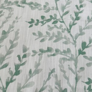 May include: A white fabric with a green leafy pattern. The leaves are a watercolor style and are scattered across the fabric.