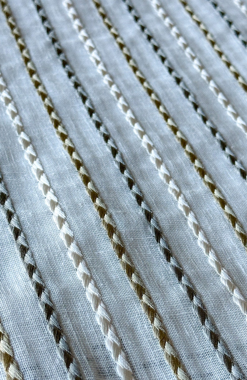 May include: White fabric with diagonal stripes of white, brown, and gray thread.