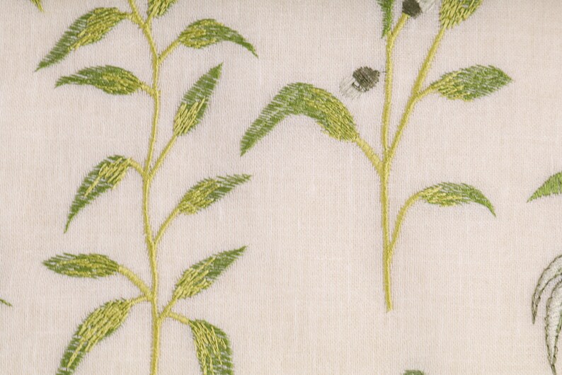 May include: A white fabric with an embroidered green leafy pattern.