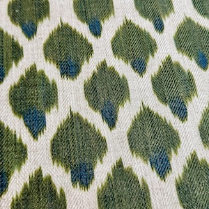 May include: A white fabric with a repeating pattern of green and blue teardrop shapes.