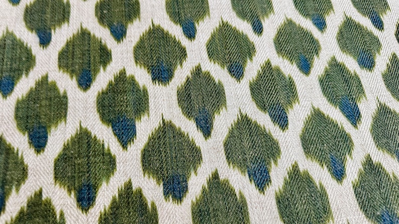 May include: A white fabric with a repeating pattern of green and blue teardrop shapes.