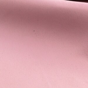 May include: A close-up of a soft, pink fabric with a subtle texture. The fabric is smooth and appears to be made of a lightweight material.