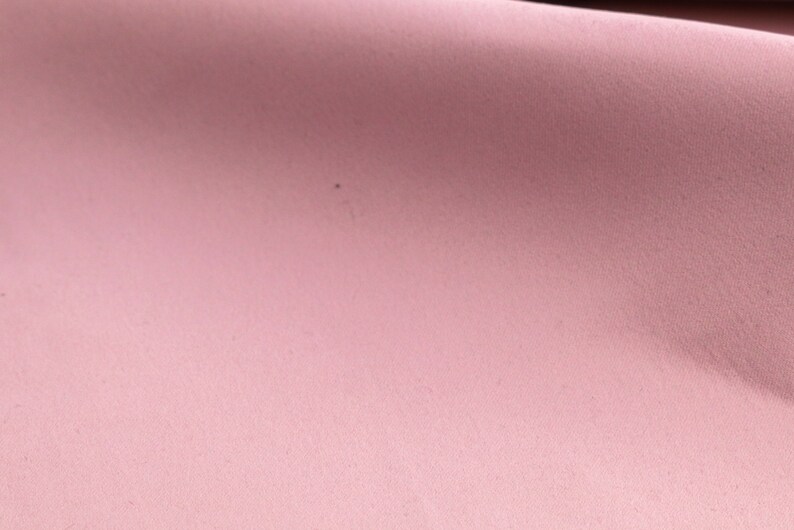 May include: A close-up of a soft, pink fabric with a subtle texture. The fabric is smooth and appears to be made of a lightweight material.