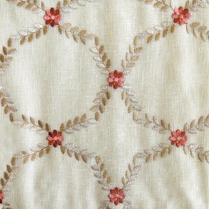 Puede incluir: Tela beige con un patr&oacute;n repetido de hojas bordadas marrones y flores rojas.