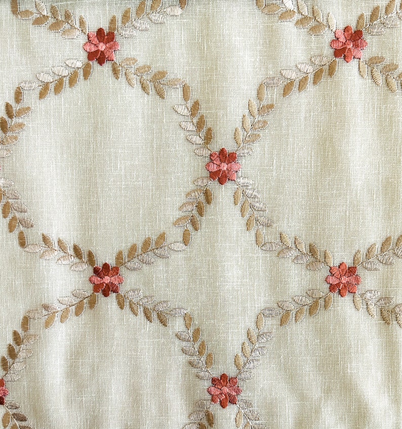 Puede incluir: Tela beige con un patr&oacute;n repetido de hojas bordadas marrones y flores rojas.