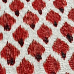 May include: A close-up of a fabric with a repeating pattern of red and black teardrop shapes on a white background.