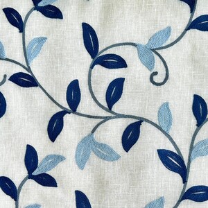 May include: White fabric with an embroidered design of blue and light blue leaves and vines.