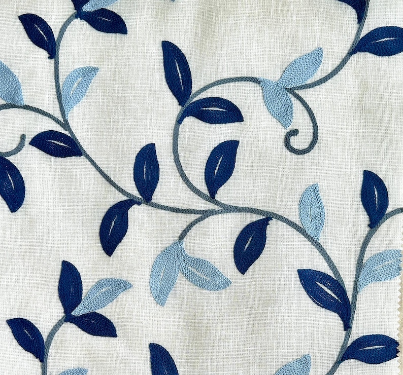May include: White fabric with an embroidered design of blue and light blue leaves and vines.