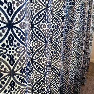 May include: A set of blue and gray patterned curtains with a geometric design. The curtains are made of a soft, woven fabric and have a subtle sheen.