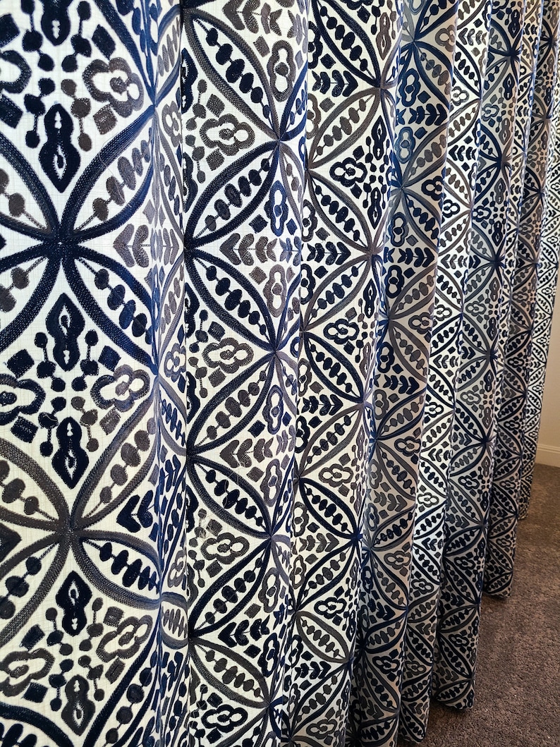 May include: A set of blue and gray patterned curtains with a geometric design. The curtains are made of a soft, woven fabric and have a subtle sheen.
