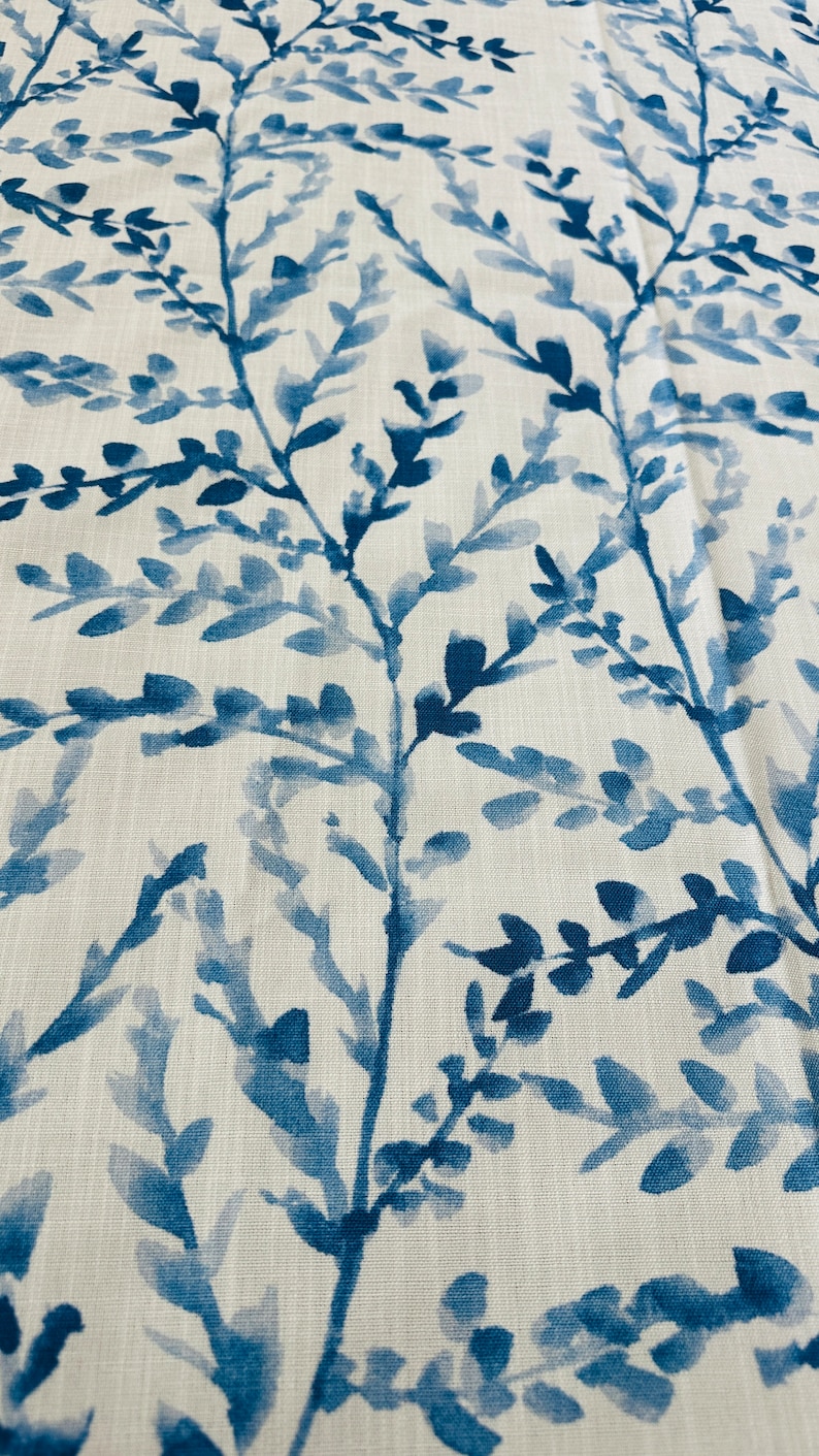 May include: Close-up of a fabric with a repeating pattern of blue watercolor-style branches and leaves against a white background. The design has a natural, organic feel, suitable for home decor or apparel.