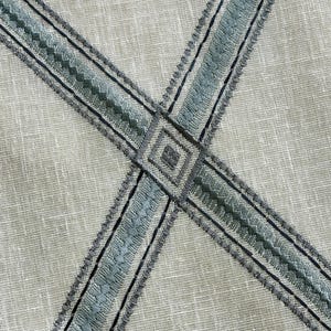 K&ouml;nnte beinhalten: Nahaufnahme eines hellgrauen Stoffes mit einem Kreuzmuster aus blauem und grauem Stickband.