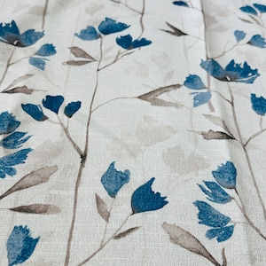 Pu&ograve; includere: Un tessuto bianco con un motivo floreale blu. I fiori sono stilizzati e hanno un effetto acquerello.