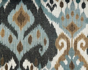 May include: A close-up of a fabric with a blue, brown, and white ikat pattern. The fabric has a textured surface and a woven look.