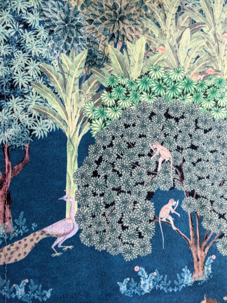 May include: A blue fabric with a colorful jungle scene featuring a peacock, monkeys, and trees. The fabric has a vintage style.