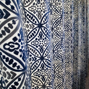 May include: Close-up of a white curtain with a blue and gray geometric pattern. The curtain is made of a soft, textured fabric.