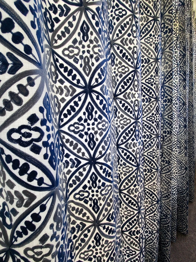 May include: Close-up of a white curtain with a blue and gray geometric pattern. The curtain is made of a soft, textured fabric.