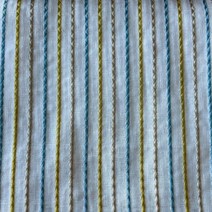 May include: White fabric with vertical stripes of yellow, blue, and beige thread.