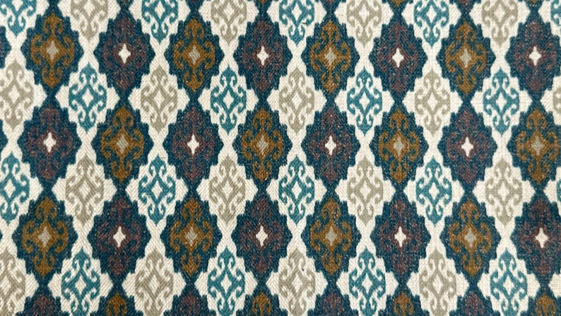 May include: A fabric with a repeating pattern of diamond shapes in shades of teal, brown, beige, and white. The pattern is intricate and features a stylized floral design.