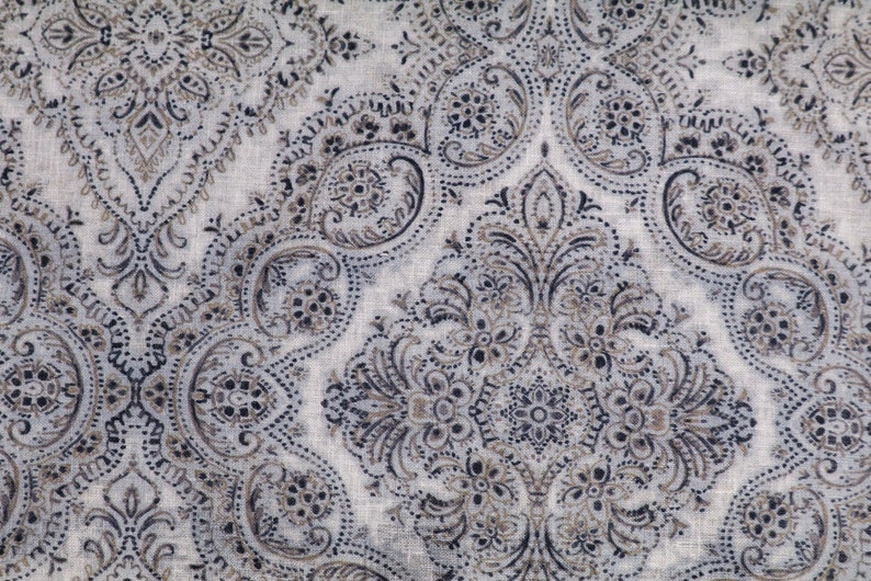 May include: A white fabric with a paisley pattern in shades of brown and black.