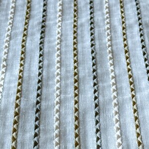May include: White fabric with vertical stripes of white, brown, and gray thread.