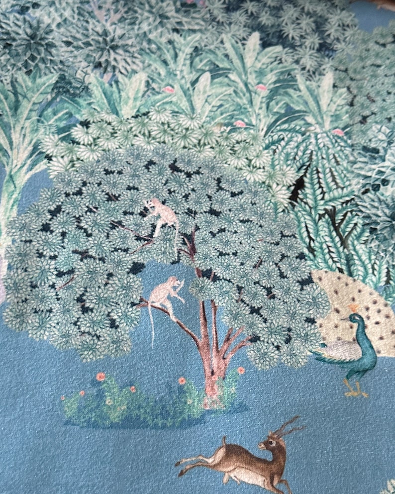 May include: A blue and green patterned fabric featuring a peacock, deer, and monkeys in a tree. The background is a light blue colour.