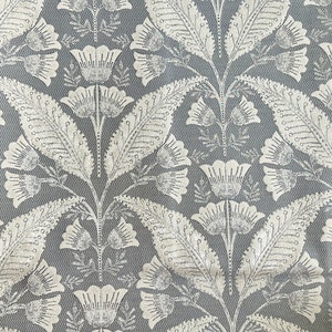 Pu&ograve; includere: Un tessuto grigio e bianco con un motivo ripetitivo di fiori e foglie stilizzati. Il tessuto ha una texture a spina di pesce sottile.
