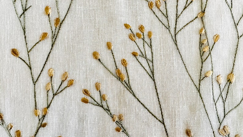 May include: White fabric with a delicate embroidered design of gold sprigs and leaves.