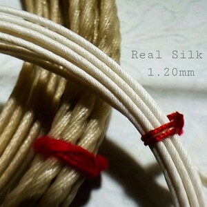 May include: Close-up of two bundles of silk cord. One is light beige, the other white. The white cord is 1.20mm thick and bound with red thread. The text "Real Silk" is visible. A craft supply.