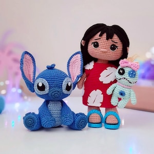 May include: Crocheted dolls of Lilo, Stitch, and a Stitch-like doll. Lilo wears a red dress with white flower shapes and blue sandals. Stitch is blue with large ears and sits on the ground. The Stitch-like doll is light blue with a pink bow.