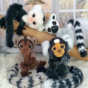 May include: A collection of handmade plush monkey toys in various colors and patterns. The monkeys have long tails, detailed faces, and are posed in different positions. The plush toys are on a white fluffy surface, with a window and decorative stars in the background.