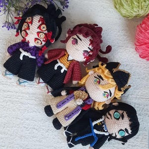 Peut inclure: Quatre personnages d'anime en crochet avec des cheveux et des vêtements de différentes couleurs. Les personnages sourient tous et ont de grands yeux.