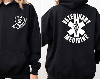 May include: Black hoodie with a front pocket and hood. The front features a white stethoscope design with a paw print and the text "Dr. Wrightson". The back displays a white emblem with the words "VETERINARY MEDICINE".