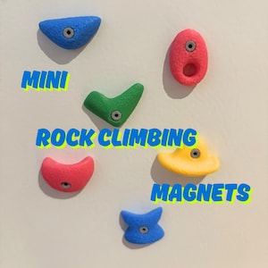Puede incluir: Una colección de coloridos mini imanes de escalada en azul, rojo, verde y amarillo. La palabra "MINI" está encima de una presa de escalada verde, y las palabras "ROCK CLIMBING MAGNETS" se muestran en azul.