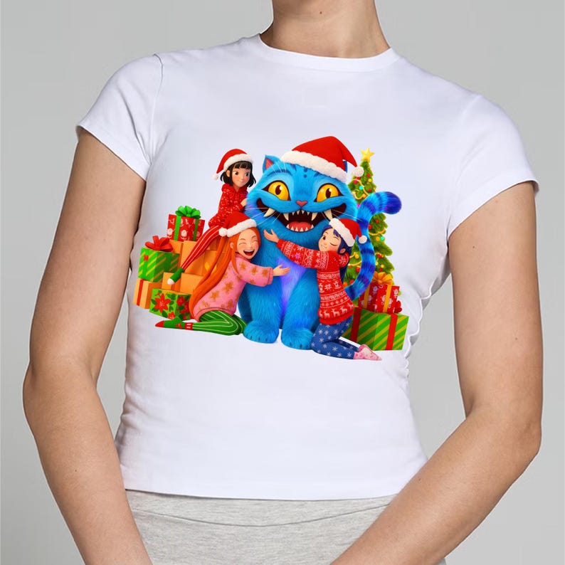 K&ouml;nnte beinhalten: Wei&szlig;es T-Shirt mit einem weihnachtlichen Motiv. Das Design zeigt eine blaue Katze mit Weihnachtsm&uuml;tze, umgeben von Kindern und Geschenken. Ein Weihnachtsbaum ist ebenfalls im Hintergrund zu sehen.