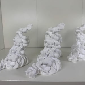 Könnte beinhalten: Vier weiße, abstrakte, wolkenförmige Skulpturen. Die Skulpturen haben ein strukturiertes, geschichtetes Aussehen mit abgerundeten Formen und einer glatten Oberfläche. Sie sind auf einer weißen Oberfläche angeordnet, was auf eine minimalistische Ästhetik hindeutet und wahrscheinlich dekorative Objekte sind.