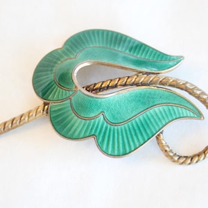 Peut inclure: Broche vintage en forme de feuilles, avec un cadre en métal argenté et un émail vert vif. La broche présente un motif de feuilles nervurées et une tige torsadée dorée. Un bijou unique.