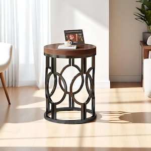 May include: A round side table with a dark brown wooden top and a black metal base. The base features a geometric design of interlocking ovals. A small screen displays an image on the table's surface.