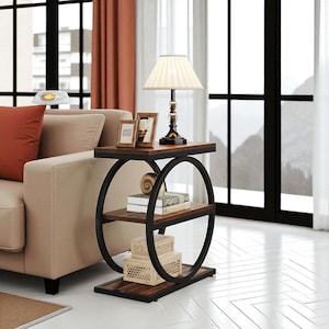 May include: A modern side table with a dark brown tabletop and two lower shelves. The table has a black metal frame with two circular supports. A lamp, picture frames, and decorative items are on the top shelf.