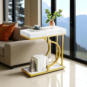 May include: A modern side table with a white marble-look top and a lower shelf. The table has a gold-colored metal frame with a unique curved design. A vase with greenery and books are displayed on the table. The table measures approximately 30 inches long.