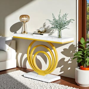 May include: A modern console table with a white marble top and a gold-colored, circular base. The table is decorated with a glass lamp, a clear glass sphere, a book, and a vase of greenery. The table is 48 inches long.