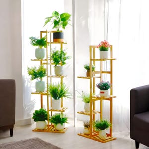 May include: Two tall, wooden plant stands with multiple shelves, each holding a variety of potted plants. The stands are made of natural bamboo and have a light brown color. The plants are a mix of green and flowering varieties.