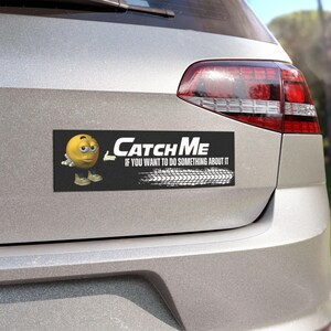 May include: A black rectangular bumper sticker with the text "Catch Me" in white, along with the phrase "If you want to do something about it." A yellow cartoon character and tire tracks are also featured.