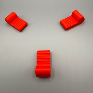 Puede incluir: Tres tumbonas en miniatura de color rojo brillante con un diseño acanalado.